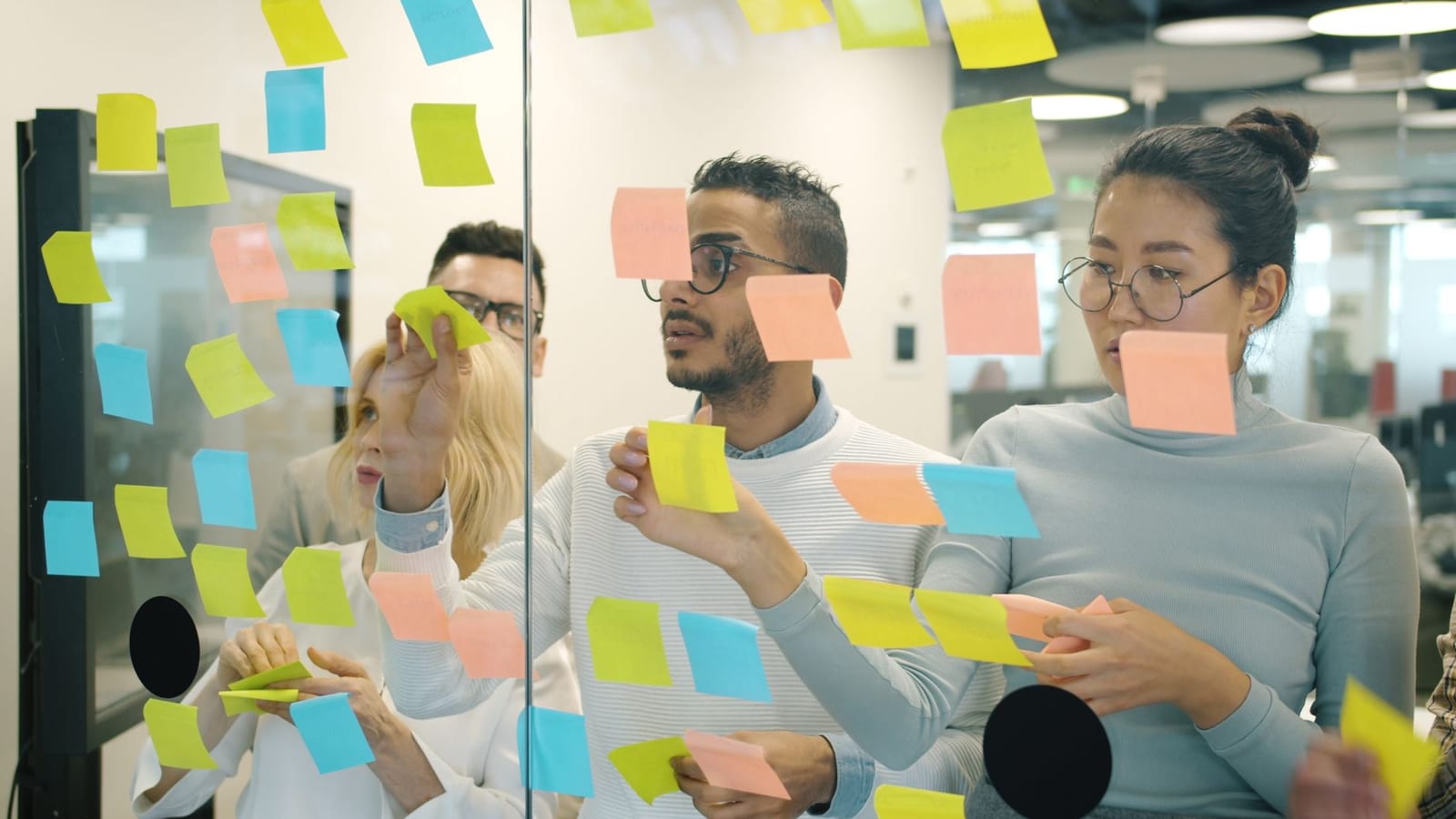 A marketing team arranging colour-coded sticky notes on a glass wall while planning an ABM strategy