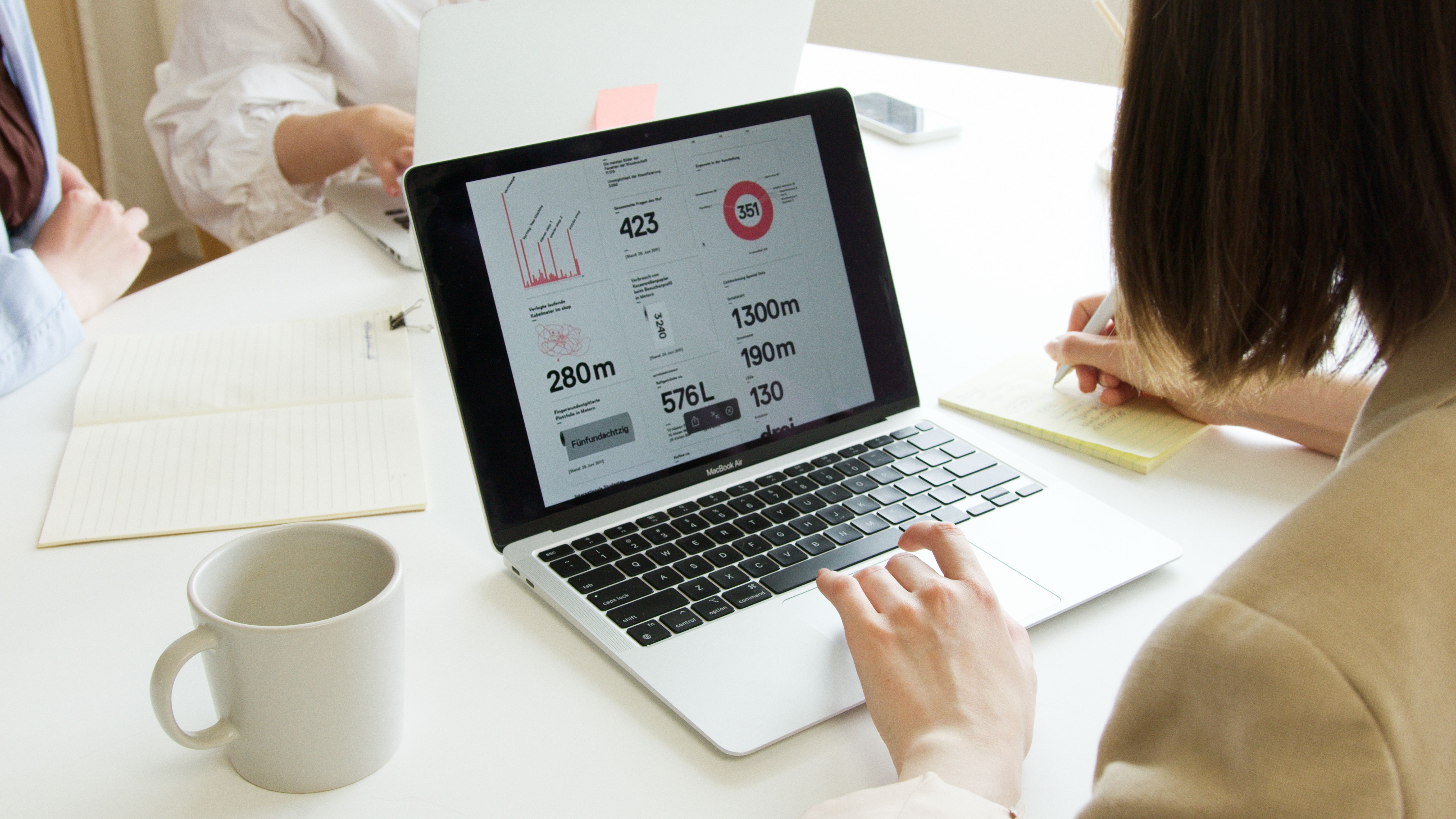 A marketer reviewing B2B search engine marketing campaign data on a laptop while taking notes