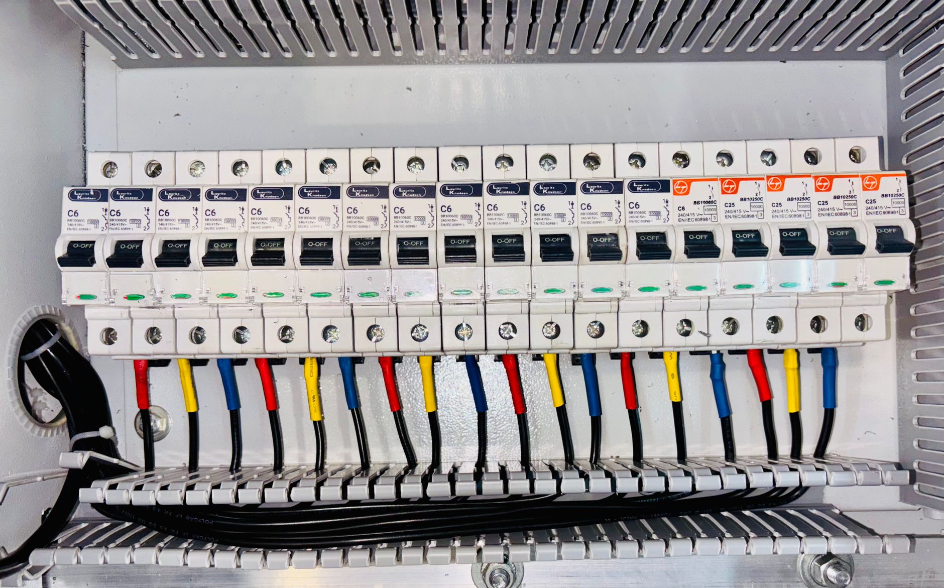 An electrical circuit breaker panel with colour-coded wiring