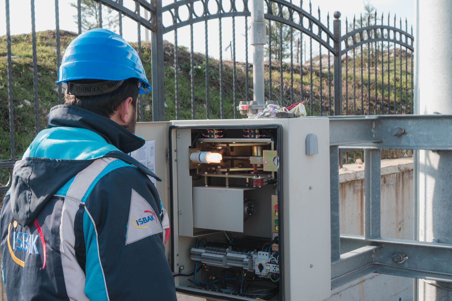An electrician in a hard hat inspecting an outdoor fuse box enclosure, the kind of job Vaughan electrician Google Ads campaigns are built to generate