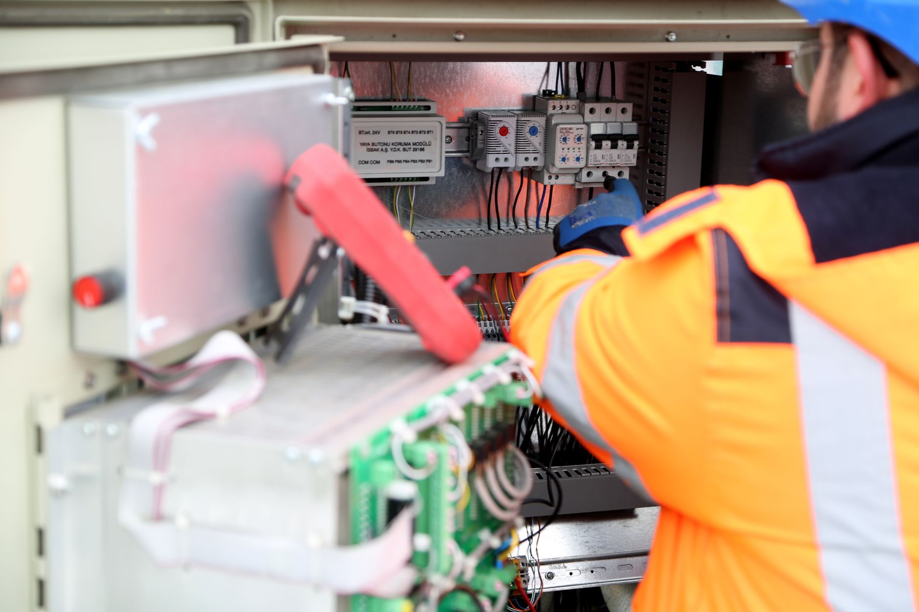 An electrician in a hi-vis jacket working inside an open electrical panel, testing wiring and breakers — the kind of work behind electrician Google Ads in Vaughan