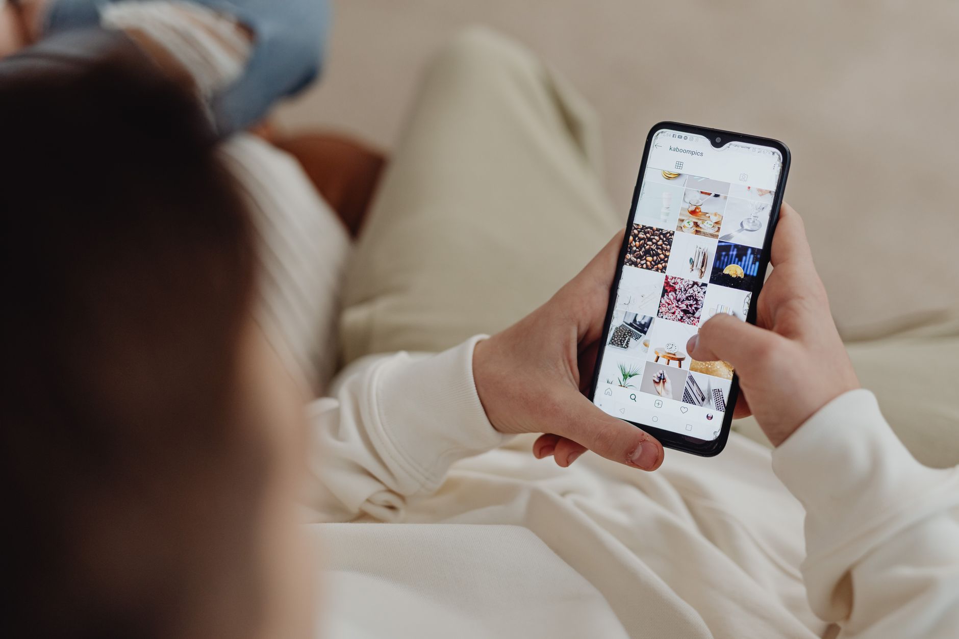 A person scrolling an Instagram grid on a phone, the kind of social feed where Facebook ads vs Google ads reach buyers differently