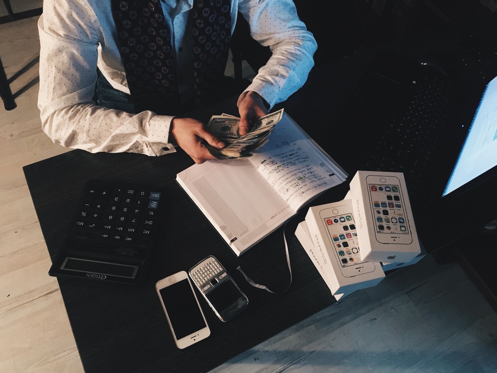 A small business owner counting cash and using a calculator while working out how to create a marketing budget