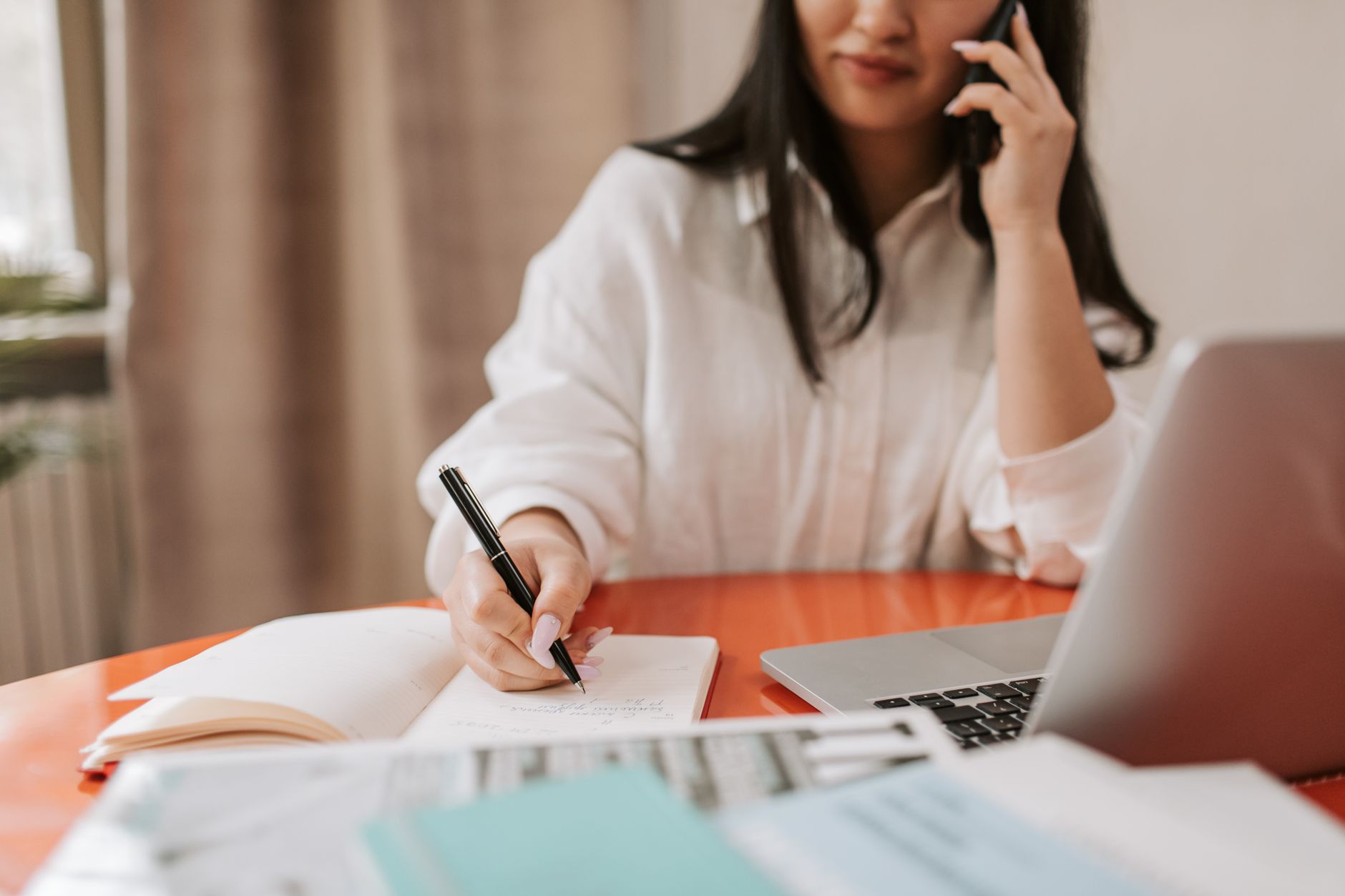 Person taking notes at a desk during a sales call, tracking the cadence for following up with leads without being annoying