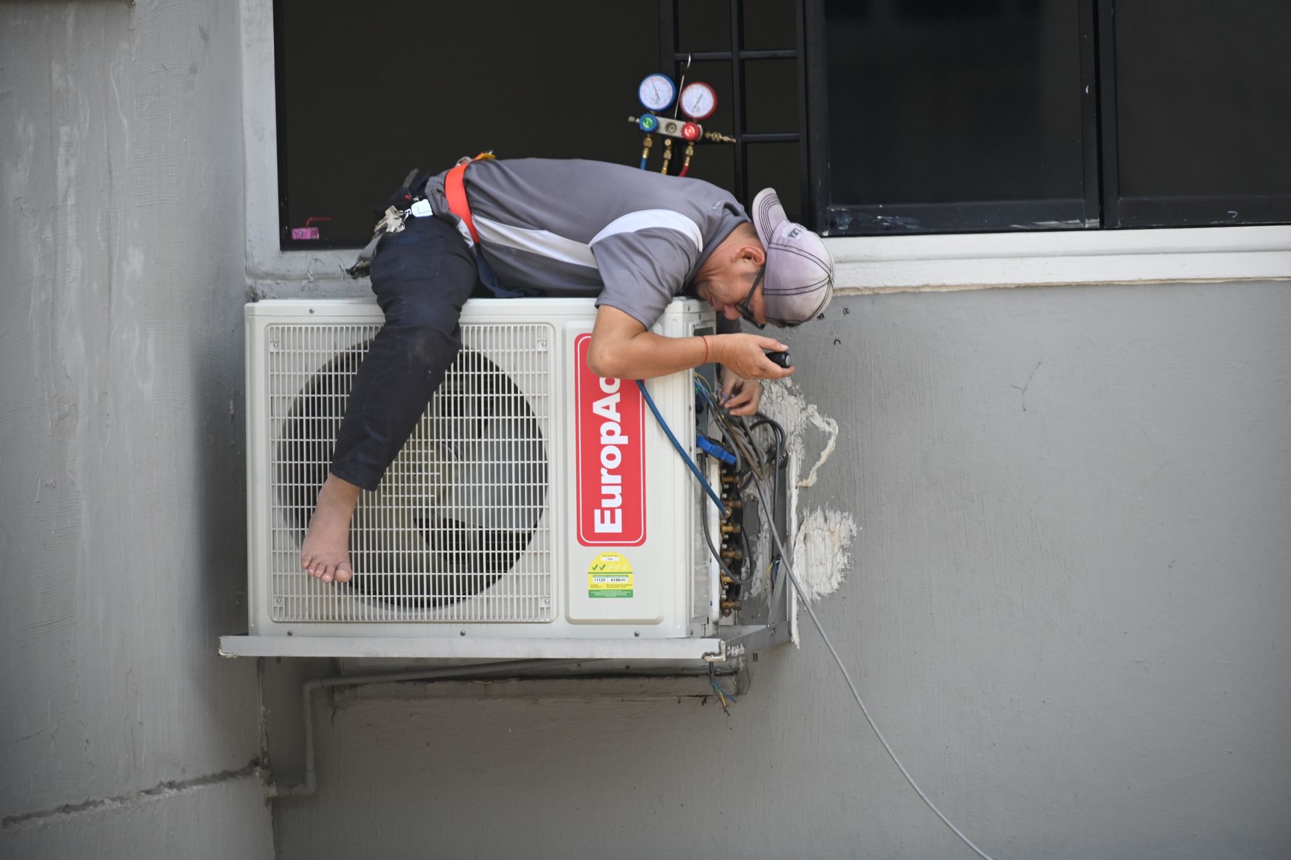 An HVAC technician repairing an air conditioning unit on a service call, the kind of booked job lead tracking has to account for