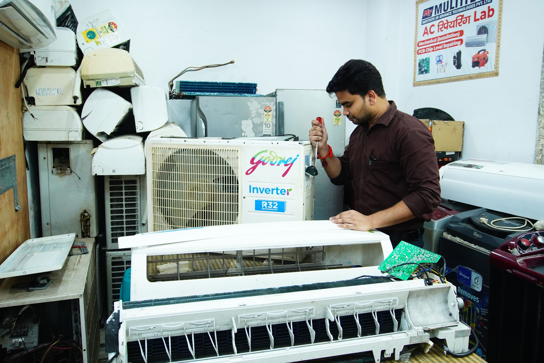 An air conditioner repair technician working on a unit in a workshop