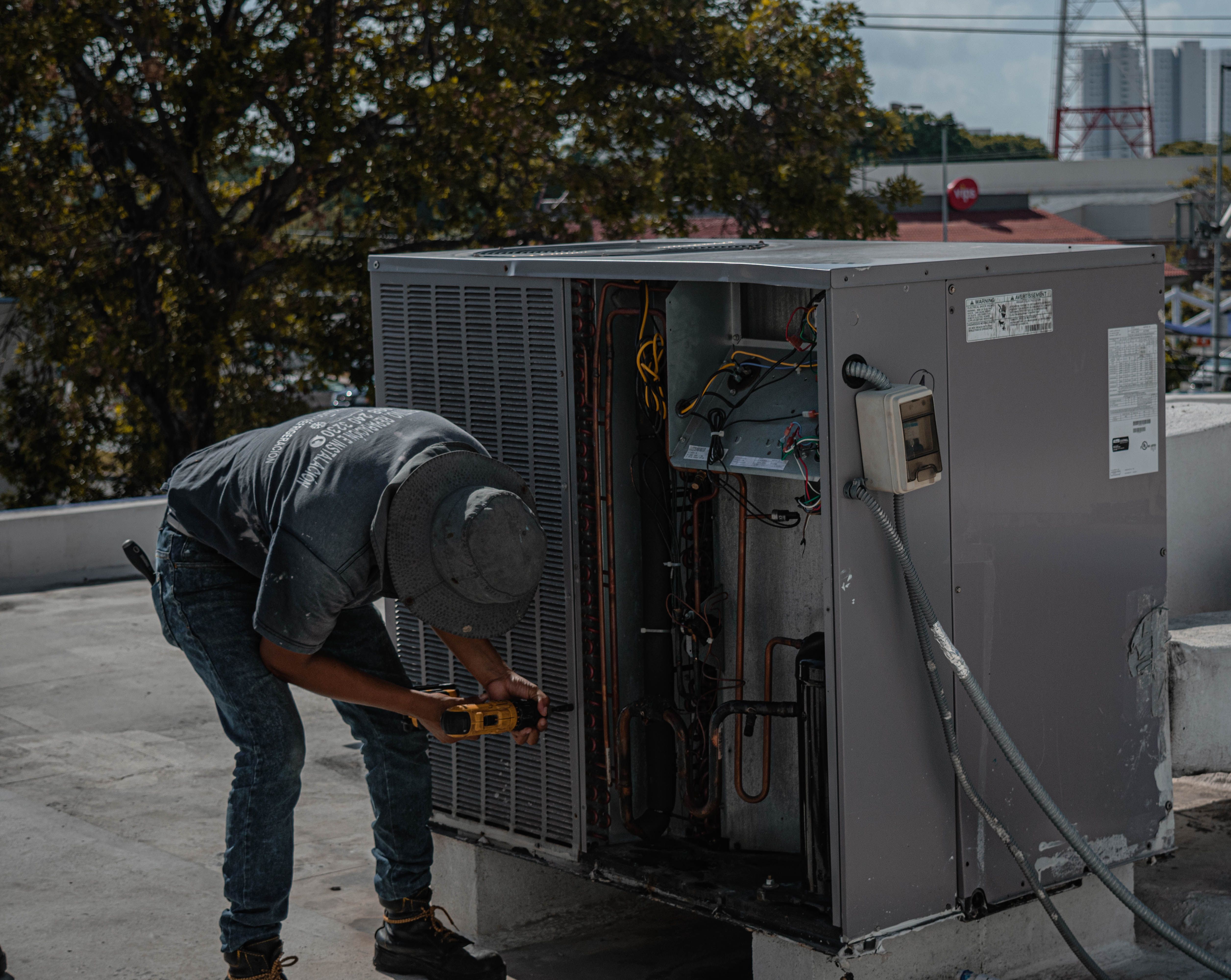 An HVAC technician repairing a rooftop air conditioning unit — the kind of real job-site photo that makes hvac social media marketing actually work