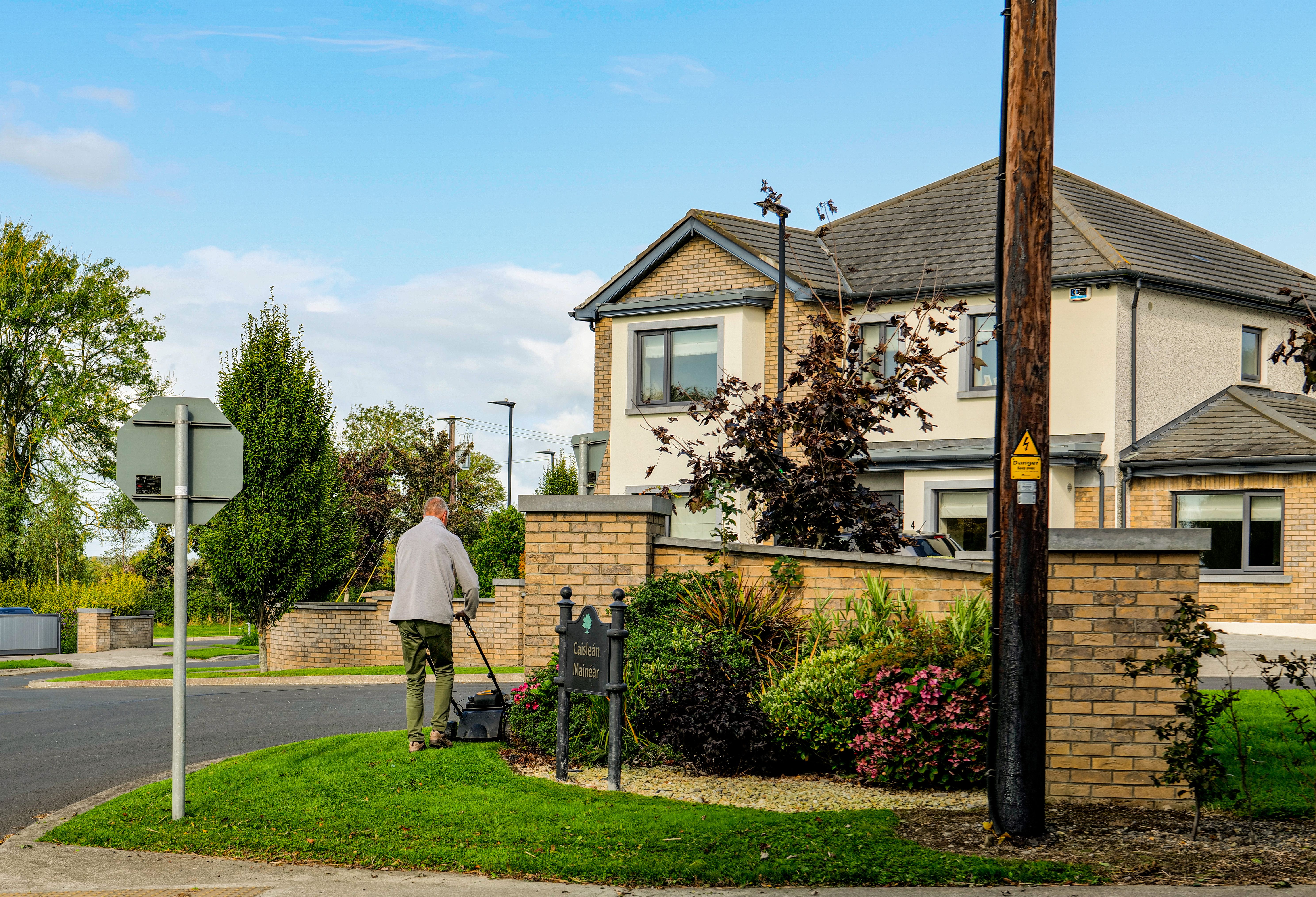 A landscaper mowing a residential lawn beside flowering garden beds — the kind of local landscaping business that benefits from Google Ads in Orillia