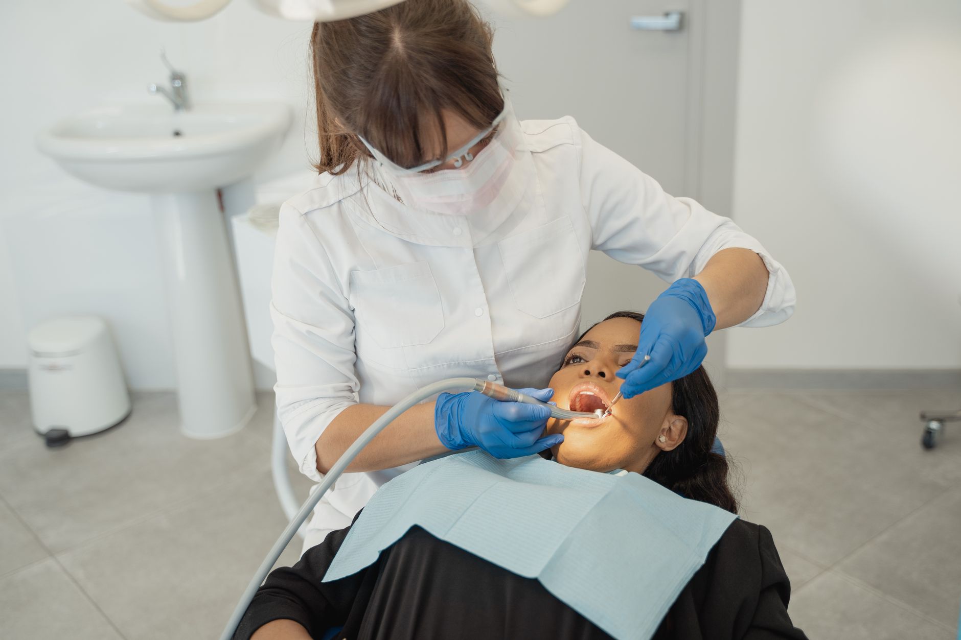 A dental hygienist checking a patient's teeth during an exam