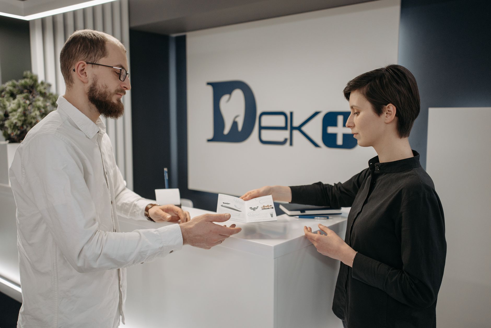 A dentist and a patient talking across the front desk at a dental clinic — the kind of practice local SEO for dentists in Barrie is meant to fill