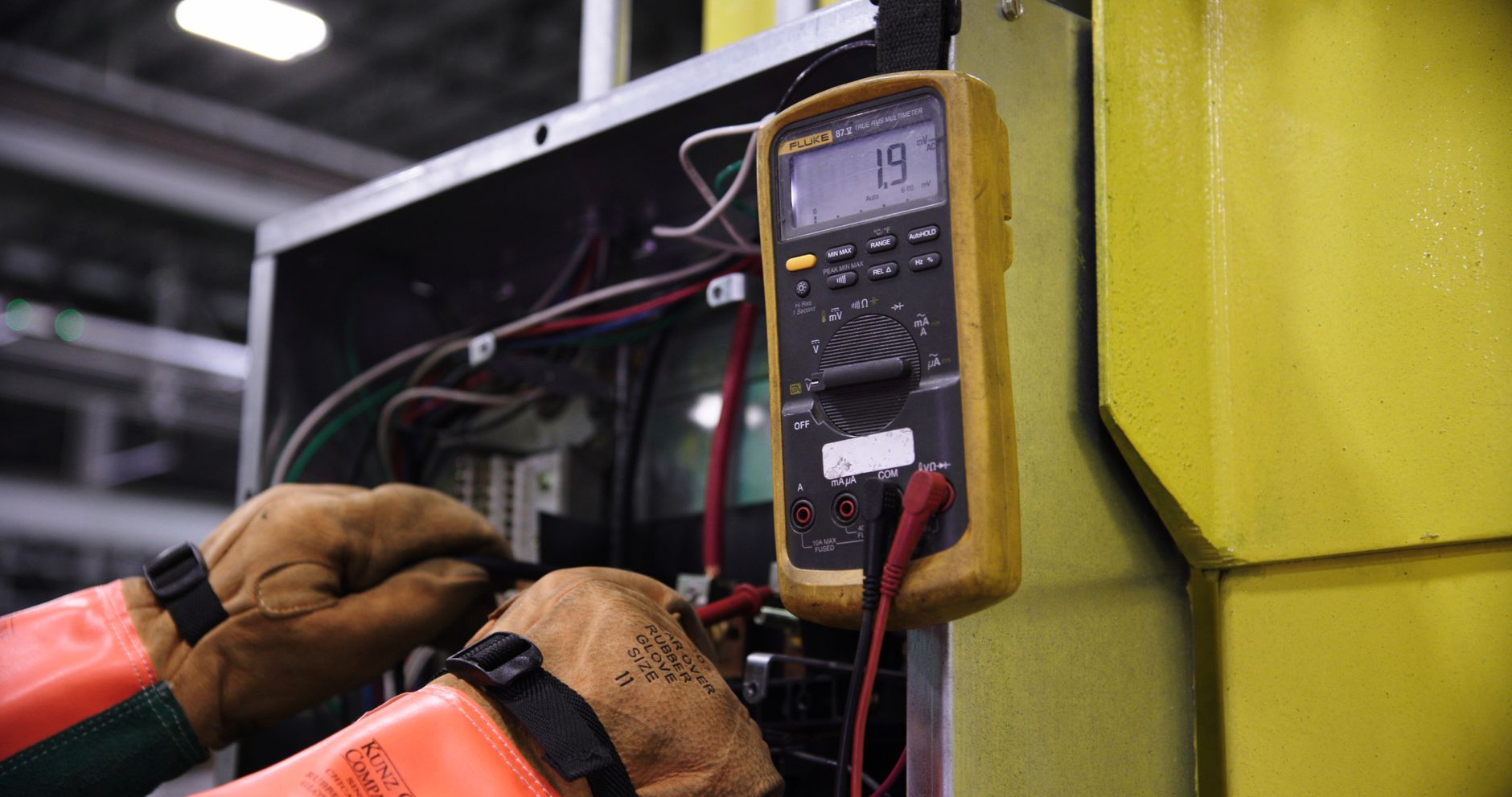 An electrician using a multimeter to test a circuit inside an electrical panel, the kind of hands-on work behind local SEO for electricians in Innisfil