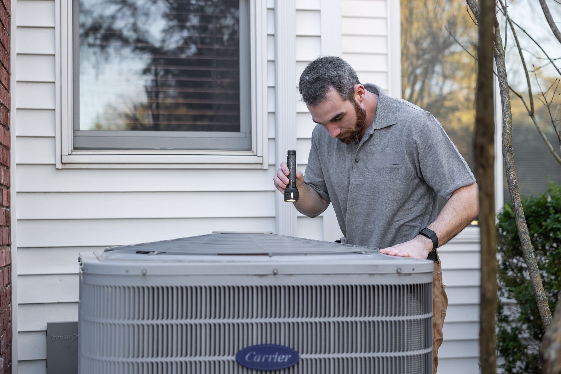 An HVAC technician inspecting an outdoor air conditioning unit: the kind of local HVAC service Thunder Bay homeowners search for online