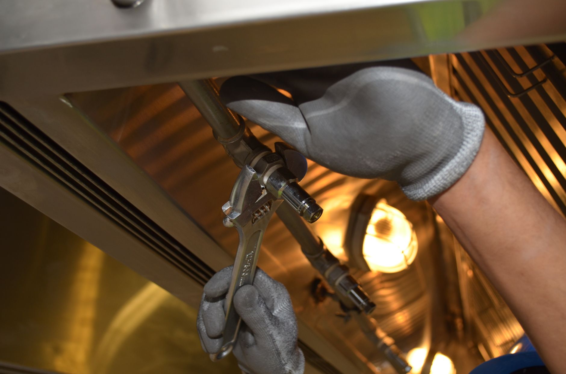 Gloved hands using an adjustable wrench on a pipe fitting, the hands-on plumbing work a Sudbury shop should show on its Google Business Profile