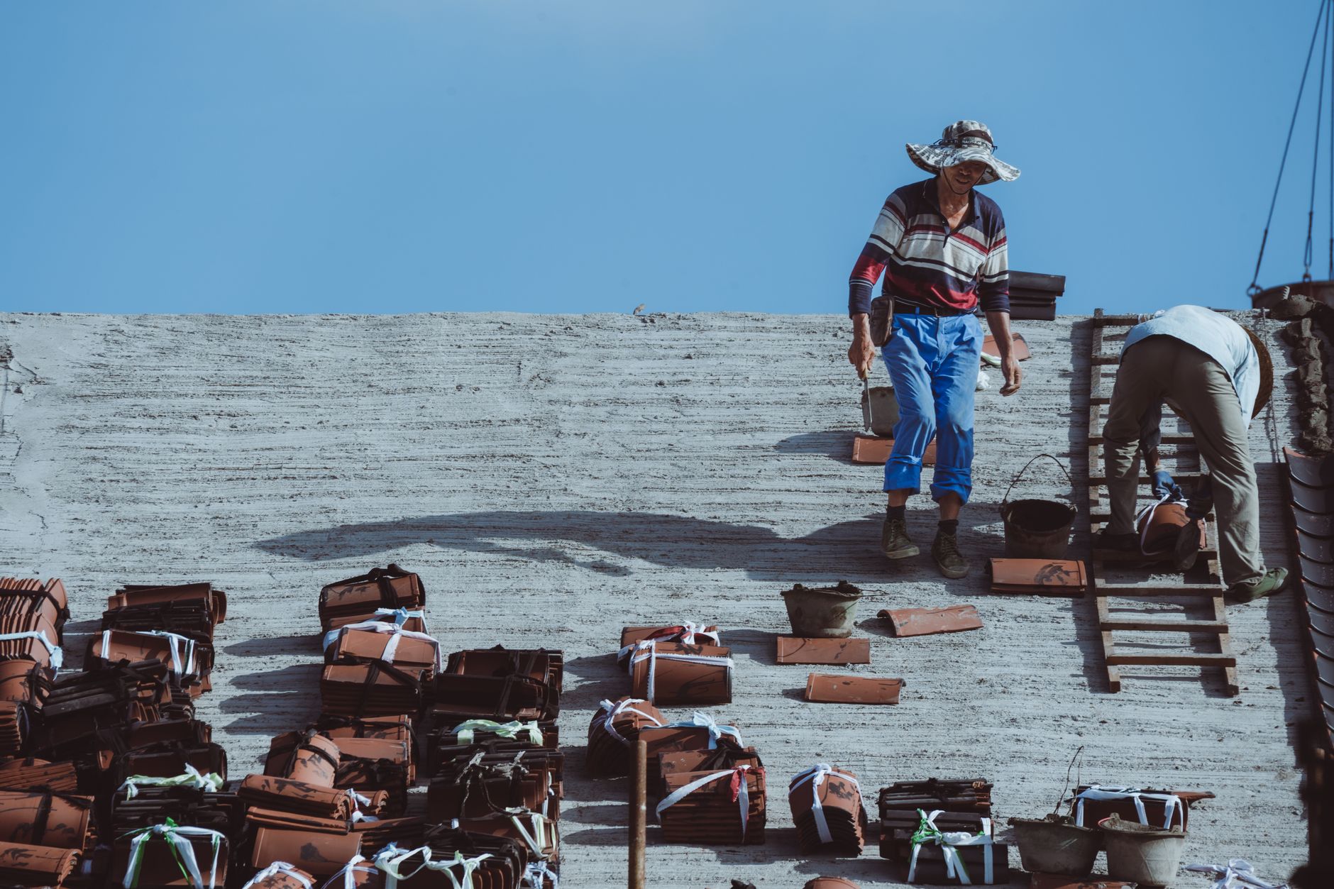 Construction workers installing roof tiles on a building